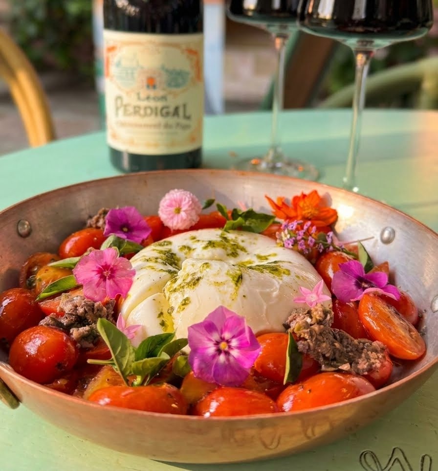Burrata cremosa Provençal servida com tomates e flores comestíveis em panela de cobre