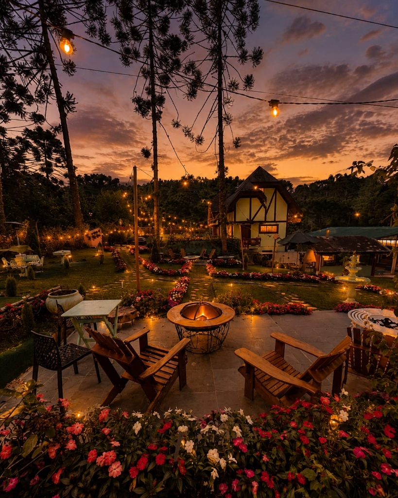 Jardim com lareira do Bistrot de Ville ao pôr do sol, luzes e flores